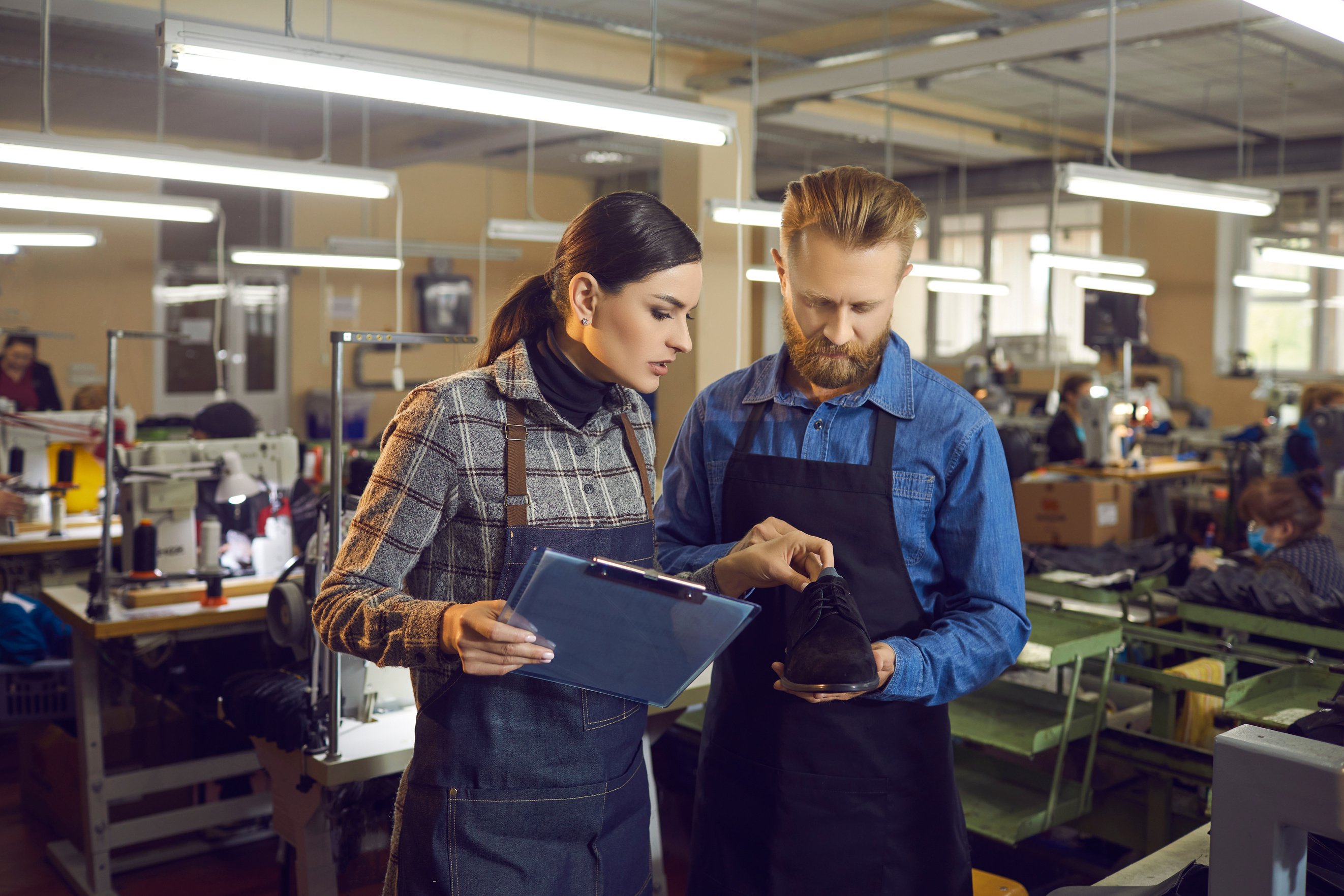 Female Master with Clipboard Checking Shoe for Defect in Shoemaker Hands